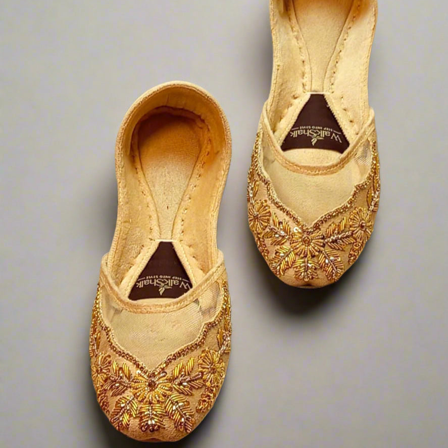 Pair of gold embroidered shoes on a beige fabric background